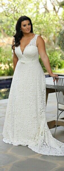 a woman standing next to a table wearing a white dress and holding onto a chair