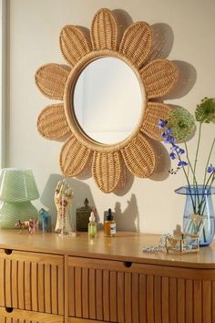 a wooden dresser topped with a mirror next to a vase filled with flowers and plants