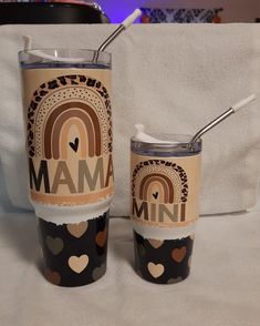 two tumblers sitting on top of a bed next to each other with the word mam printed on them