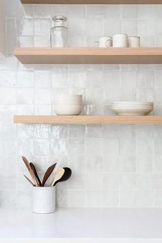 the shelves above the kitchen sink are filled with dishes and utensils, which include wooden spoons