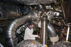 a man in white shirt working on large metal pipes