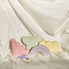 three different colored vases sitting next to each other on a white cloth covered surface