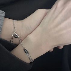 a person wearing a bracelet with charms on their wrist and holding onto the arm of another person's hand