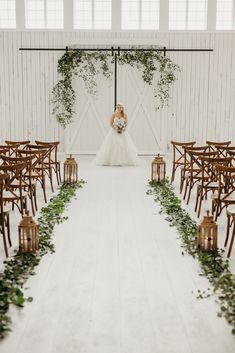 a bride and groom standing in front of rows of chairs with greenery on them