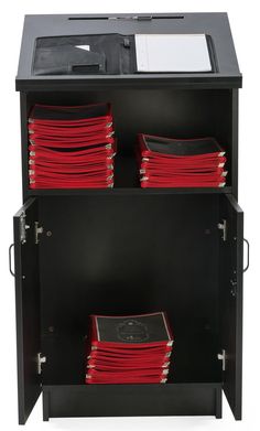 a black cabinet with red plates stacked on top of it and papers in the bottom drawer