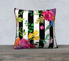 a black and white striped pillow with colorful florals on it sitting on a wooden table