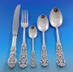 an assortment of silverware including spoons, forks and knives on a blue background