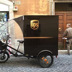 a man standing next to a black bike with an ups logo on the front and side