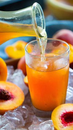 someone is pouring juice into a glass with peaches on the table next to them