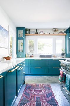 a kitchen with blue cabinets and an area rug