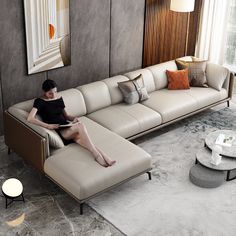 a woman sitting on top of a couch in a living room next to a table