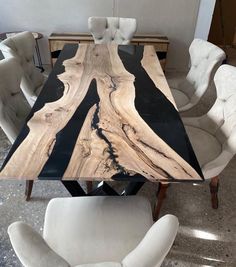 a dining table made out of wood with white chairs around it and a black marble top