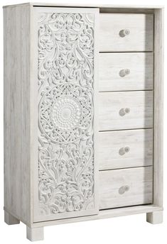 a white wooden cabinet with carvings on the front and drawers, all in carved wood