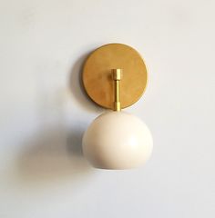 a white ball mounted on the wall next to a gold plated light fixture,