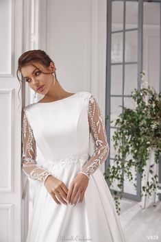 a woman in a white wedding dress leaning against a wall with her hands on her hips