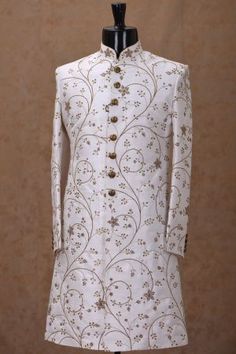 a mannequin is dressed in a white suit with gold buttons and floral designs