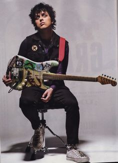 a man sitting on a stool holding a guitar