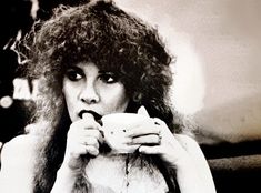 a woman with curly hair drinking from a cup