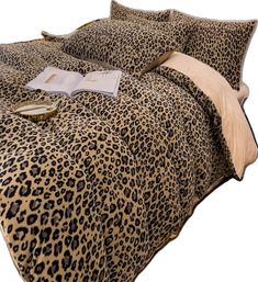 a leopard print comforter set on a bed with two pillows and an open book