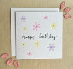 a card with the words happy birthday written in black ink on top of it, surrounded by pink and yellow flowers