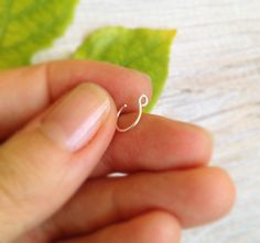 a person is holding a tiny ring in their left hand and there are green leaves on the table