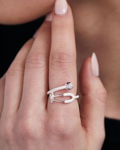 a woman's hand wearing a white ring with an arrow on the middle finger