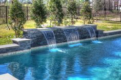 an outdoor pool with waterfall in the middle