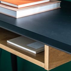 two books are sitting on the edge of a wooden table with an electronic device next to it