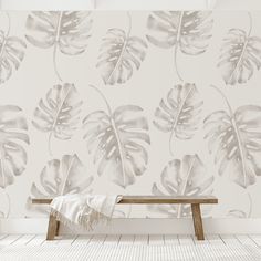 a bench sitting in front of a wall with a large leaf pattern on it