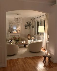 a living room filled with furniture and a chandelier hanging from the ceiling over a wooden floor