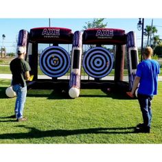 two men standing in front of an inflatable target set up on the grass