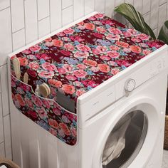 a washer and dryer in a room with flowers on the front, next to a white tiled wall