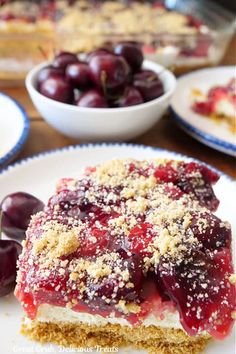 a piece of cake on a plate with cherries and other desserts in the background