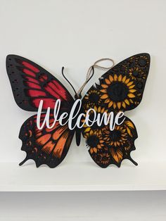 an orange and black butterfly with the word welcome on it's wings is sitting on a shelf