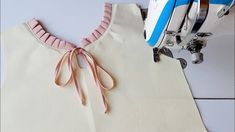 a sewing machine is next to a white shirt with pink ribbon on the front and bottom