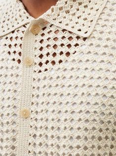 a close up of a person wearing a white crochet sweater with buttons on the collar