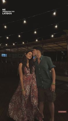 a man and woman standing next to each other on a wooden floor in front of lights