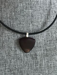 a black necklace with a wooden triangle on it's leather cord hanging from the neck