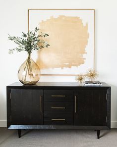 a vase filled with flowers sitting on top of a wooden cabinet