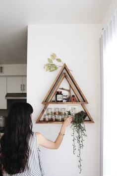 a woman is looking at some spices on the wall and she is trying to arrange them