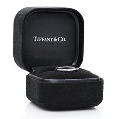 a wedding ring in a black box with the word tiffany and co on it's side