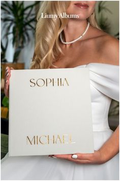 a woman holding up a sign that says sophiia and michael in gold lettering