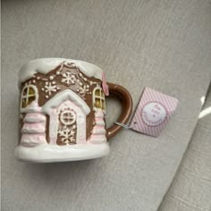 a ceramic mug with a gingerbread house on the side and a tag attached to it