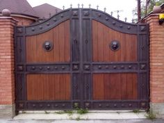 an iron and wood gate in front of a brick house