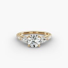 a gold engagement ring with three stones on the side and an accent diamond in the middle