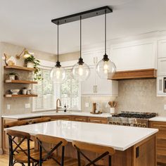 a kitchen with wooden cabinets and white counter tops, two pendant lights over the island