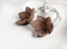 a pair of brown flower earrings sitting on top of a white surface