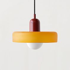 a red and yellow light hanging from a ceiling fixture with a white wall in the background