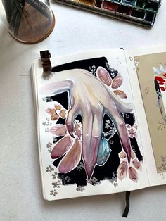 an open book on a table with paint and watercolors