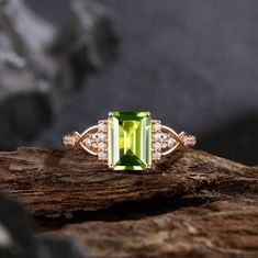 a green ring with diamonds on top of a piece of wood next to some rocks